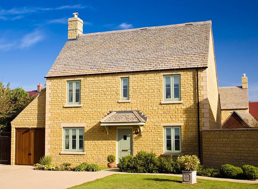 Yellow stone house with chartwell green upvc casement windows