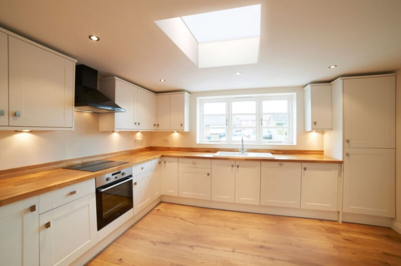A white kitchen with an oak work top, integrated oven and white window.
