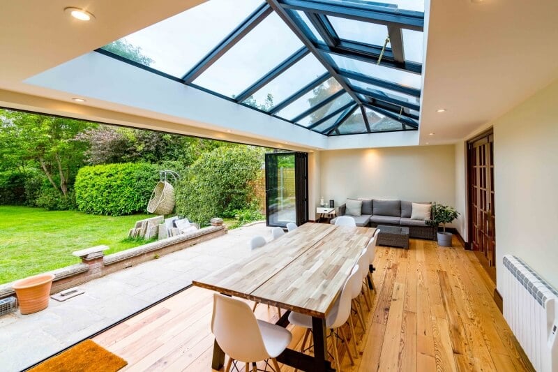 Open black bi fold doors from a oak inspired dinning area. 