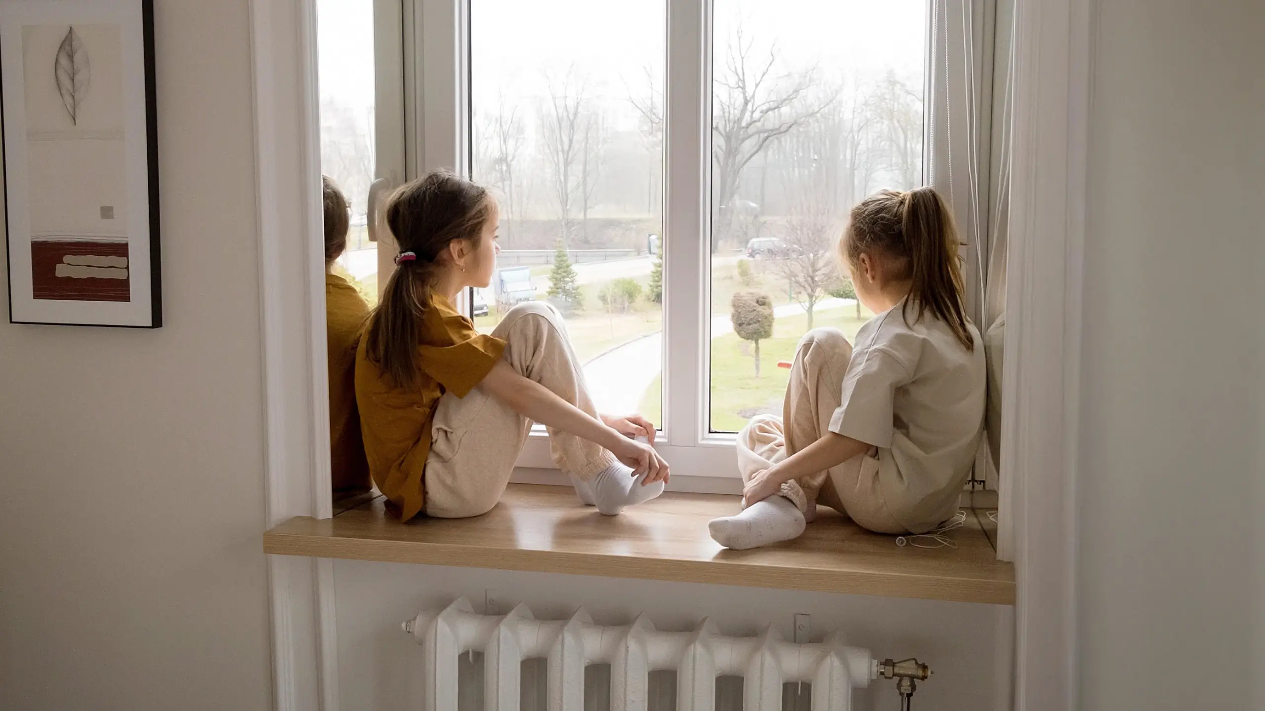 Two girls sitting on a window cill looking out of the window